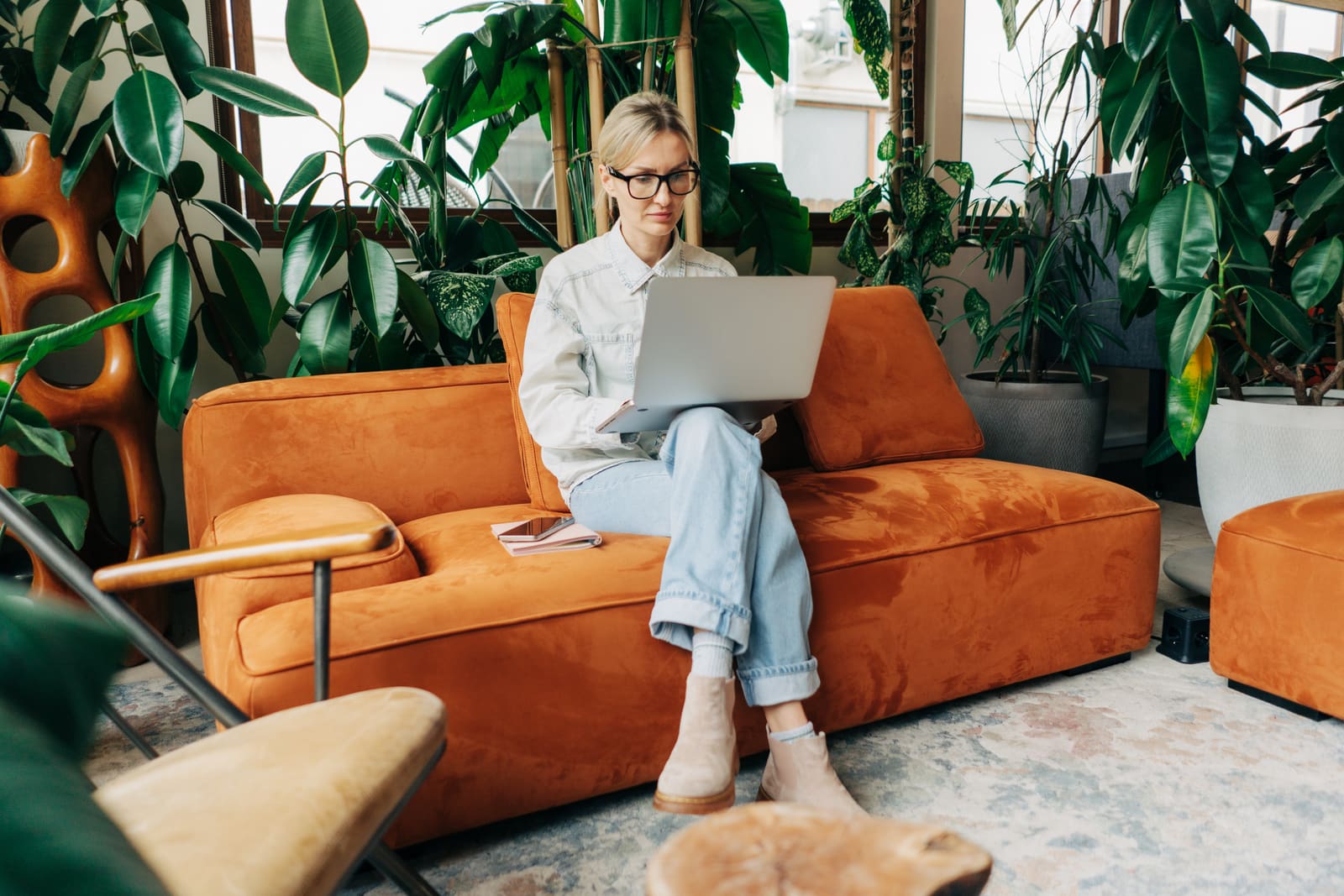 Small business owner working on an email marketing campaign on a laptop while sitting on an orange sofa