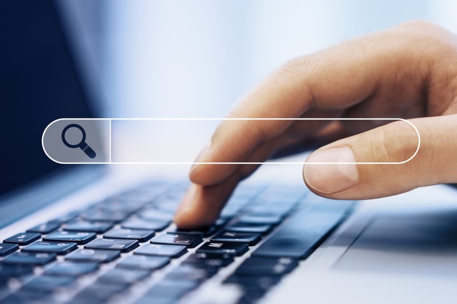 Close-up of hands typing on a laptop while managing a Google Ads campaign