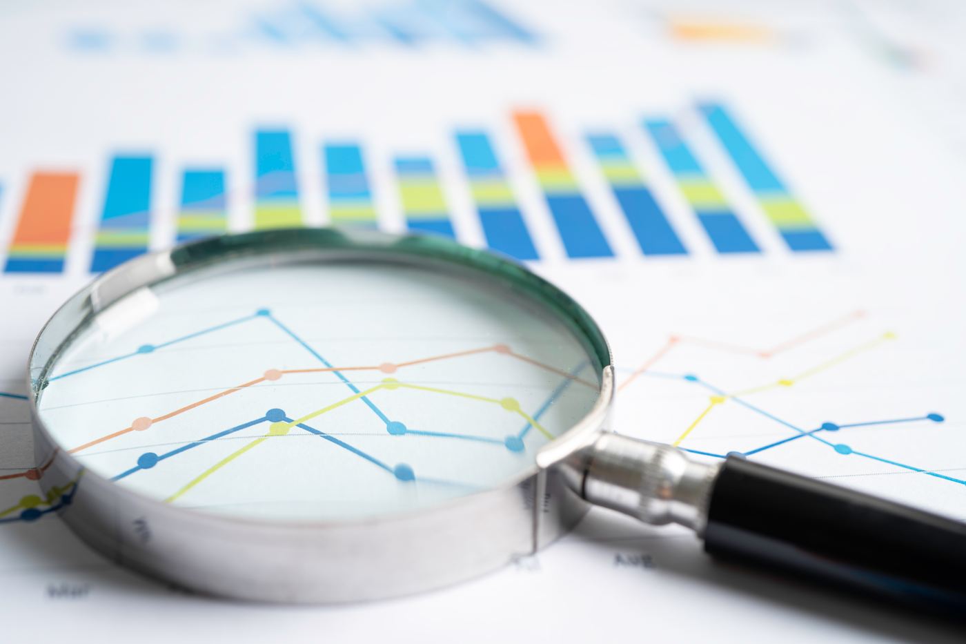 Magnifying glass over business charts and analytics data, representing SEO performance tracking and keyword research